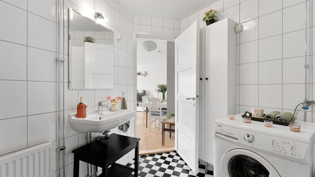 Flislagt bad med badekar og opplegg for vaskemaskin.