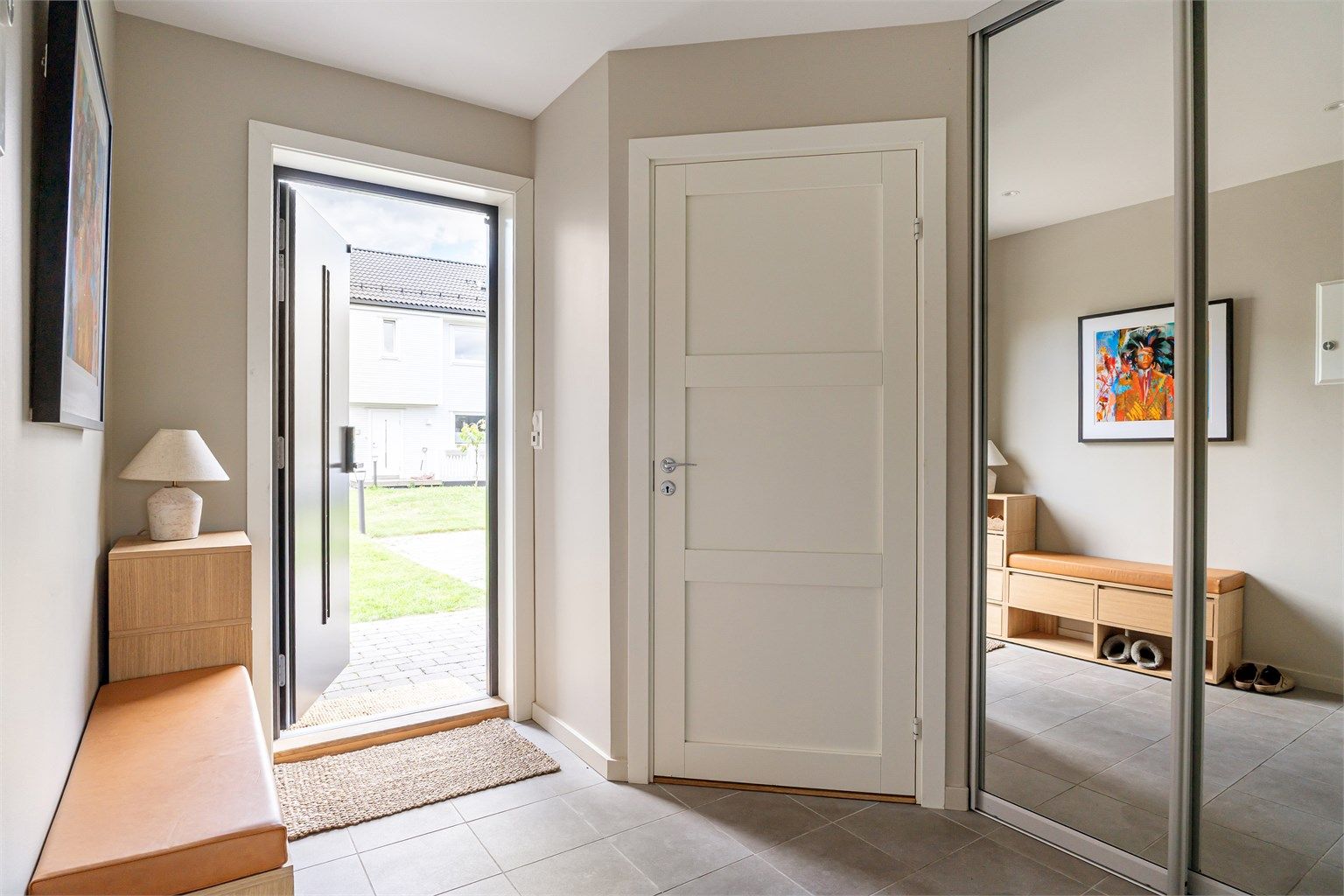Innbydende entré med flislagt gulv med gulvvarme og en praktisk skyvedørsgarderobe.