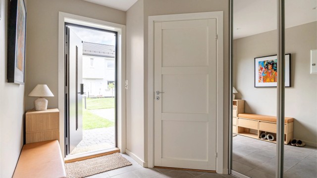 Innbydende entré med flislagt gulv med gulvvarme og en praktisk skyvedørsgarderobe.