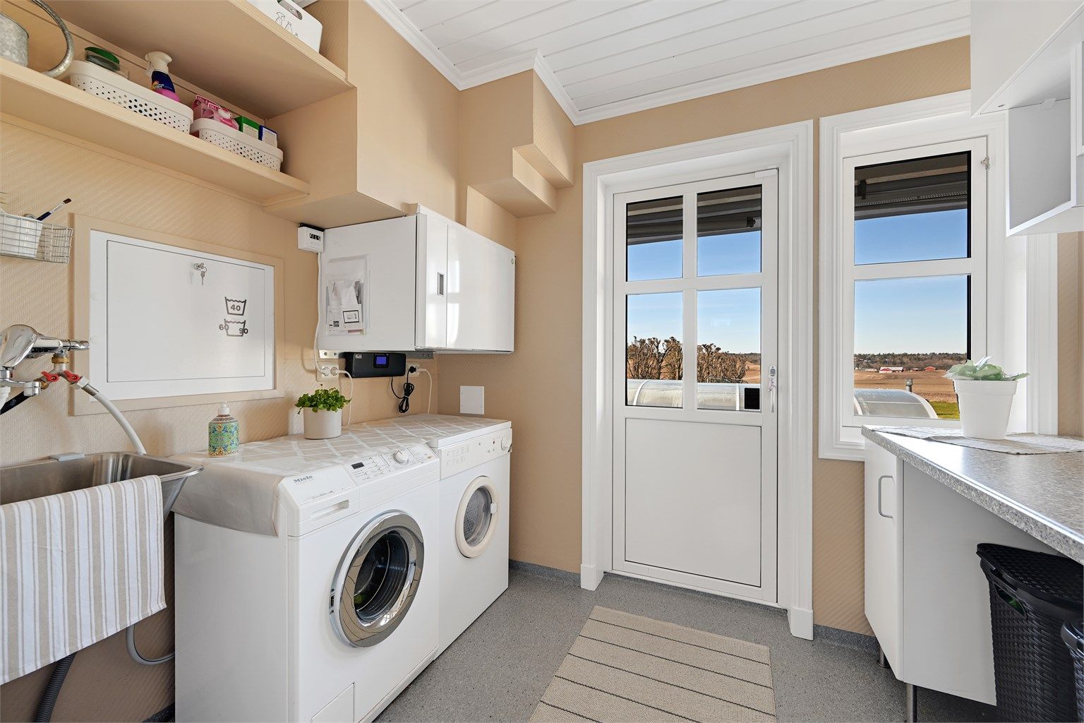 Vaskerommet har egen inngang, opplegg for vaskemaskin og tørketrommel, og huser det balanserte ventilasjonsaggregatet fra 2022.