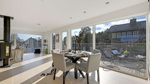 Den åpne planløsningen forener stue, spisestue og kjøkken, og bades i lys fra store vindusflater og glassdør mot balkongen.