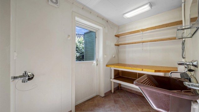 Praktisk vaskerom med flislagt gulv, gulvvarme og egen utgang.