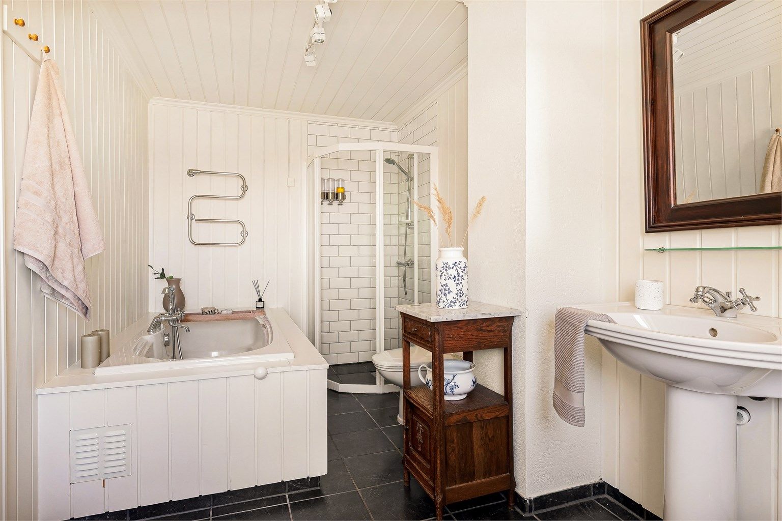 Badet er pent innredet i klassisk og tidløs stil med flis på gulv med varme, og panel på vegger.