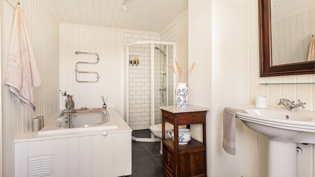 Badet er pent innredet i klassisk og tidløs stil med flis på gulv med varme, og panel på vegger.
