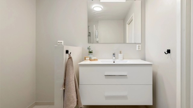 Her er det flislagt gulv med gulvvarme, dusjhjørne med glassvegger og opplegg for vaskemaskin