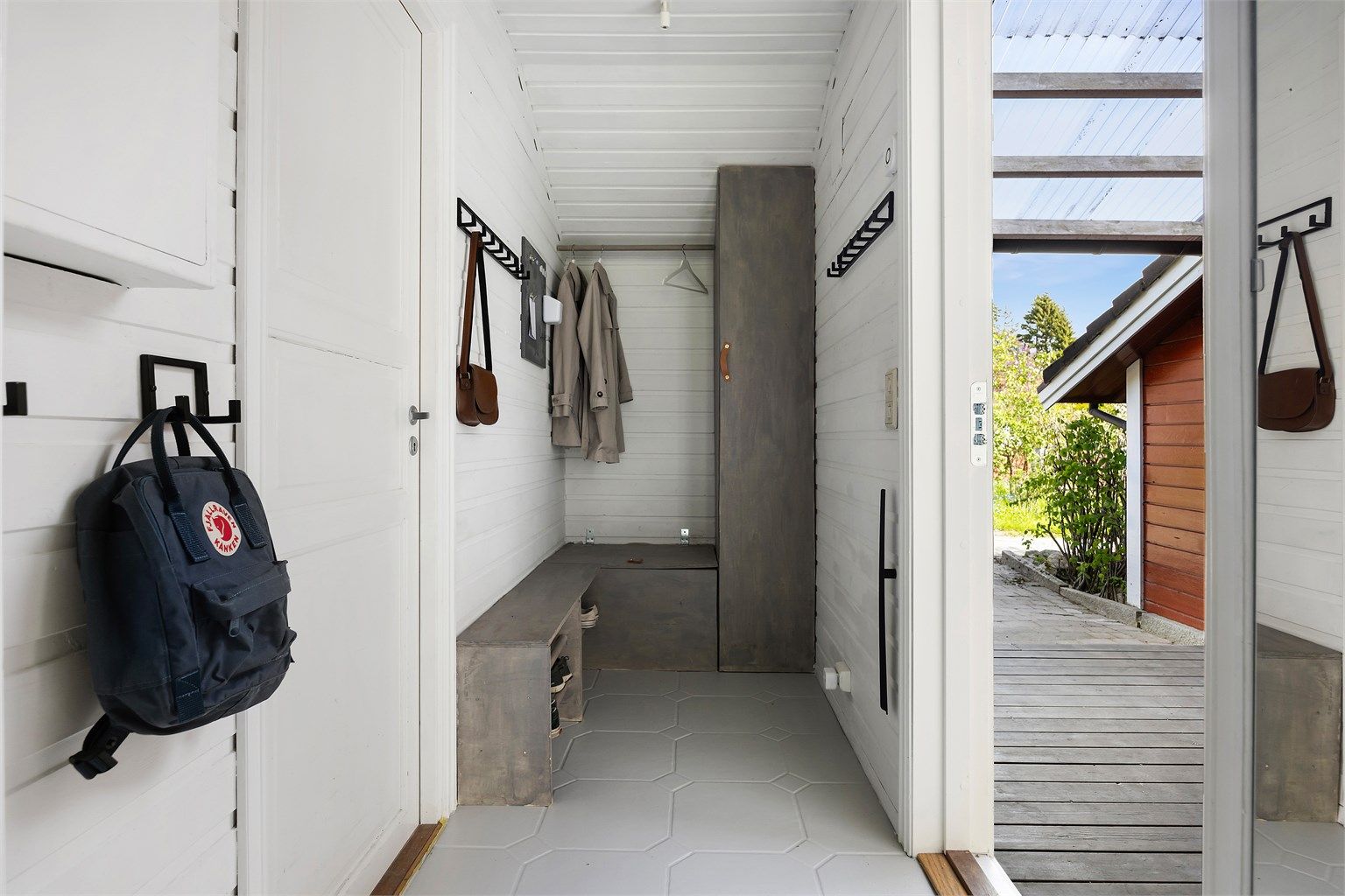 Entré med flislagt gulv og plassbygget entrémøbel