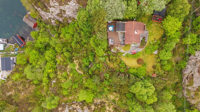 Dronebilde av eiendommen med båtopptrekk i viken nedenfor.