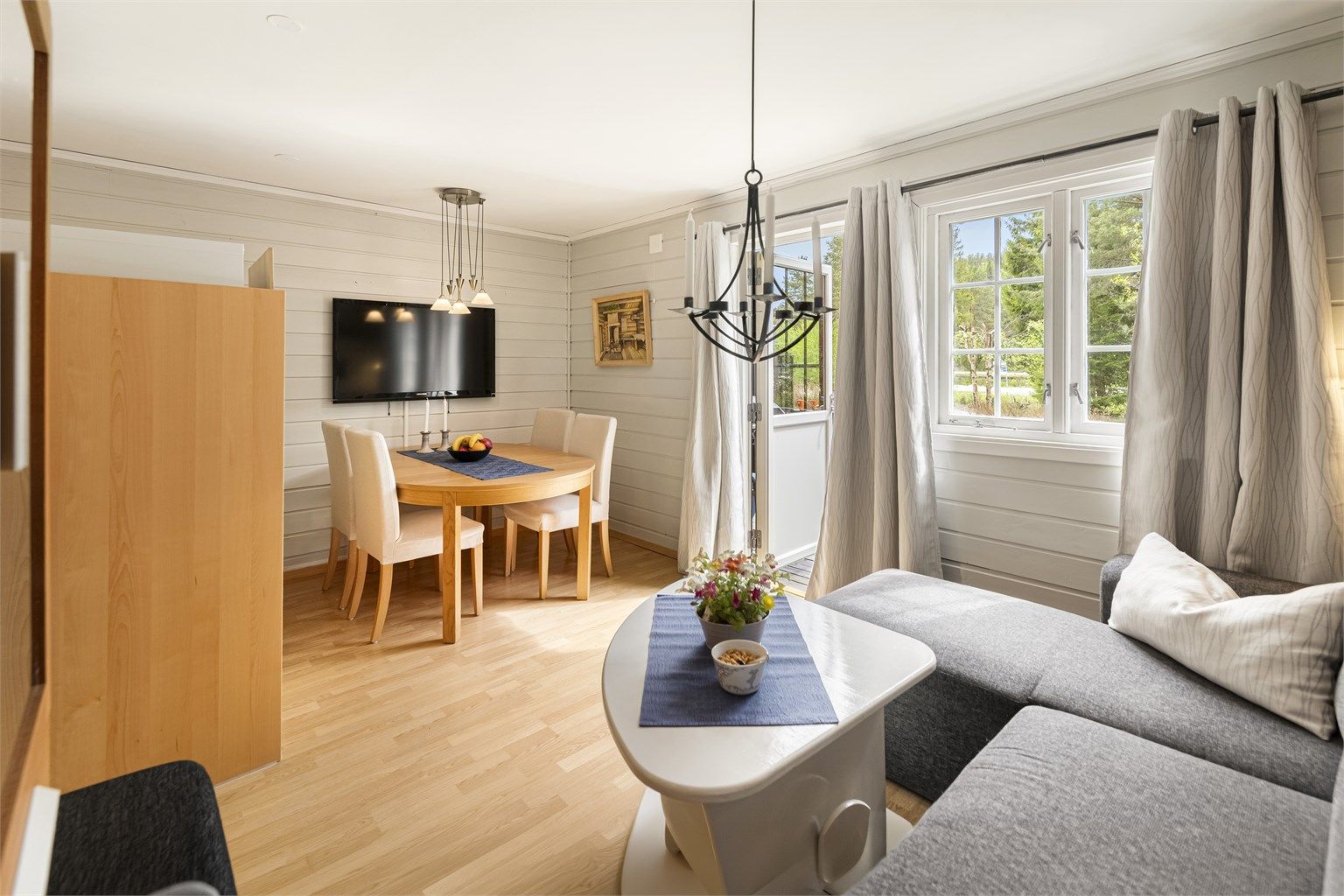Stuen har plass til både sofagruppe og spisebord. Veggene er lysmalte