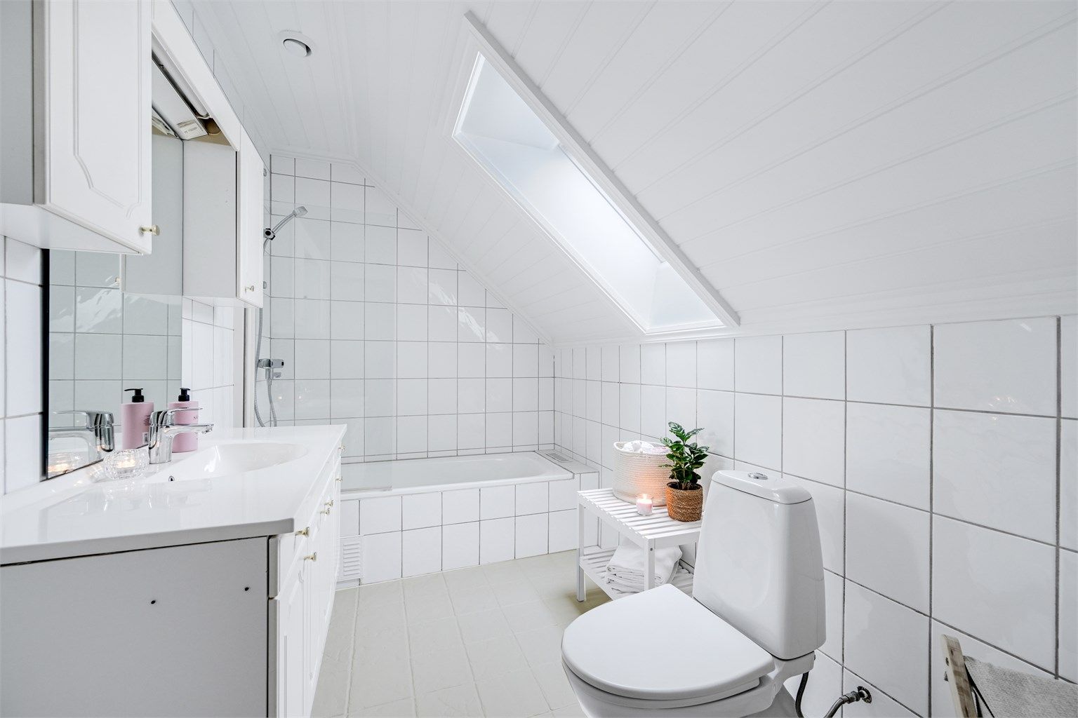 Flislagt bad med toalett, servant og badekar.