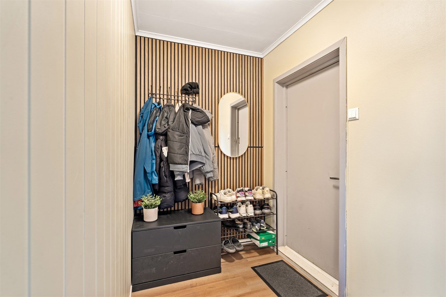 Entréen har plass til klesoppheng og skooppbevaring, og er innredet med dekorativt spilepanel.