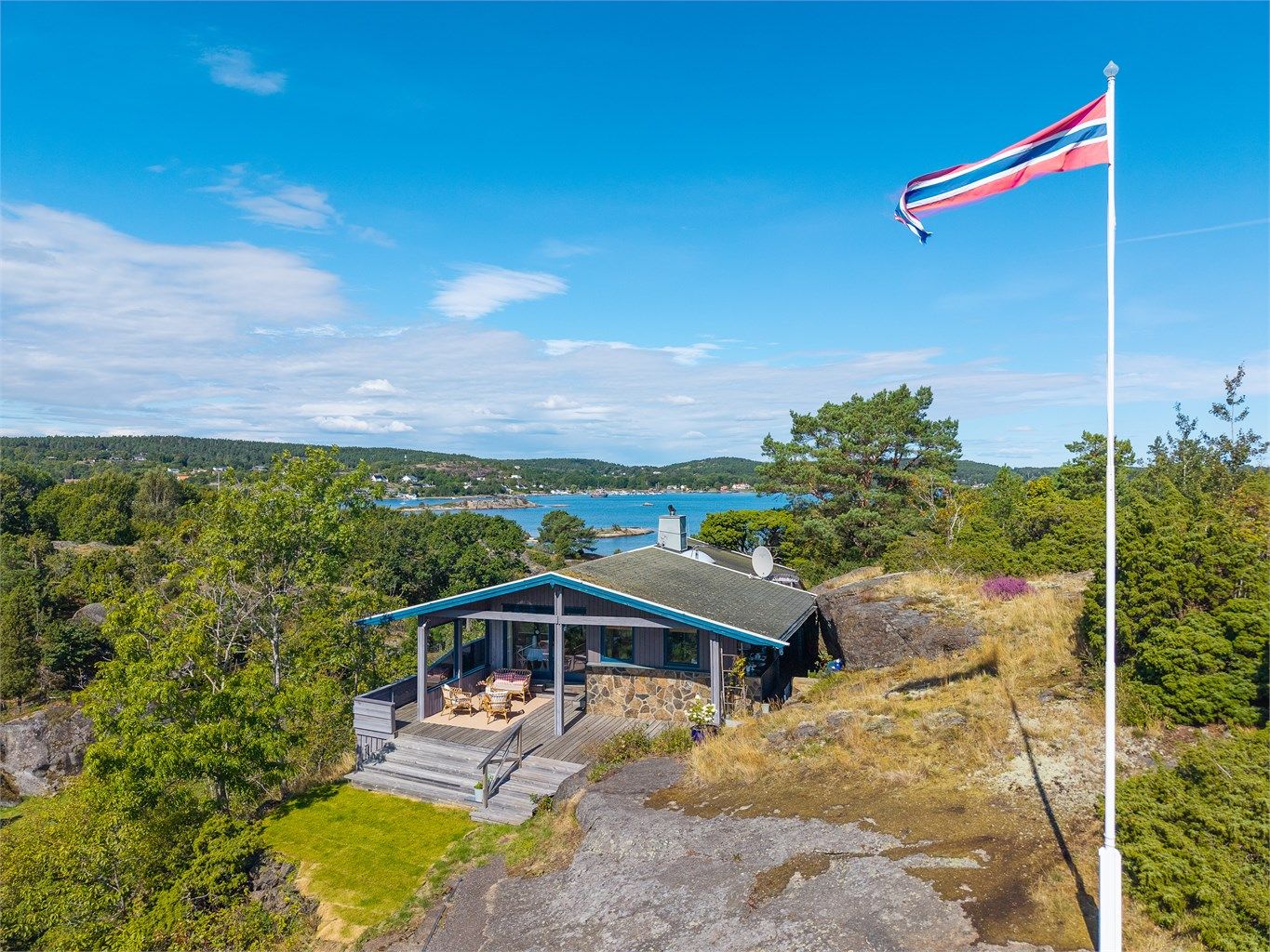 Denne flotte fritidseiendommen fra 1971 ligger høyt og fritt til, med en spektakulær sjøutsikt både mot nord og sør. Her får du sol fra morgen til kveld, vakre uteplasser og en planløsning som er både praktisk og sosial – perfekt for sommerliv med familie