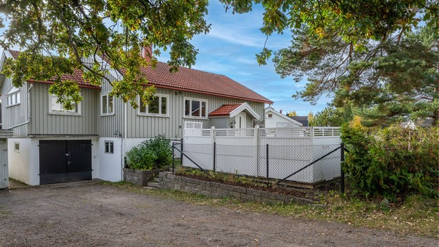 Gruset innkjørsel med integrert garasje og gode parkeringsmuligheter på tomten.