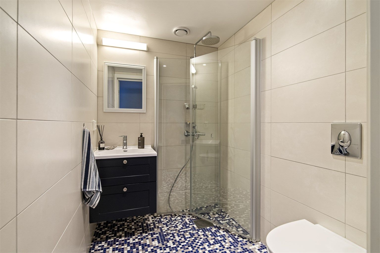 Leiligheten har to flislagte bad, begge fra byggeåret. Dette badet har gulvvarme og dusjhjørne med innfellbare dører.