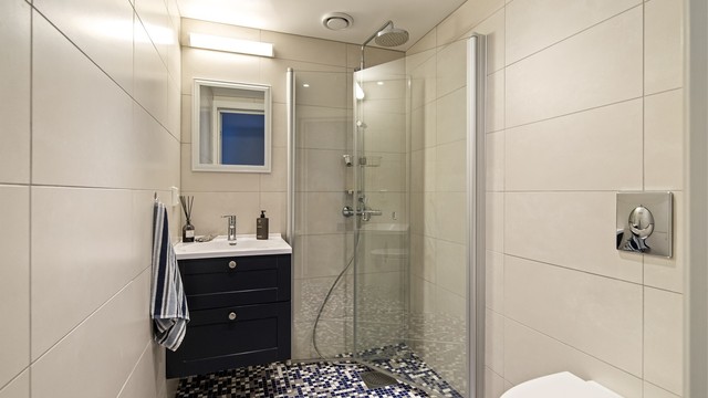 Leiligheten har to flislagte bad, begge fra byggeåret. Dette badet har gulvvarme og dusjhjørne med innfellbare dører.