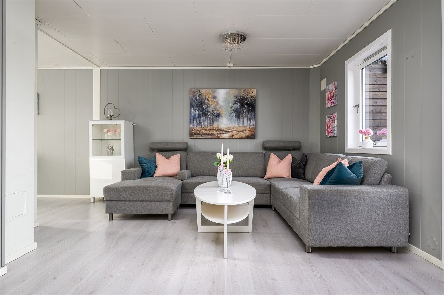 Stuen er en del av en åpen løsning mot kjøkkenet, noe som skaper en sosial og luftig atmosfære.