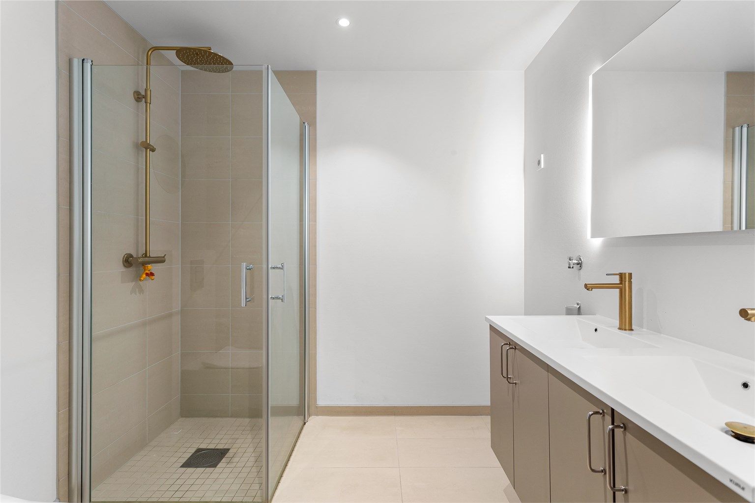 Badet har dusjhjørne med foldedører av glass samt regnfallsdusj. 