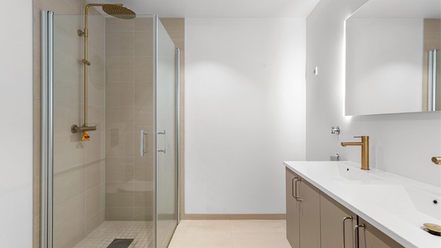 Badet har dusjhjørne med foldedører av glass samt regnfallsdusj.