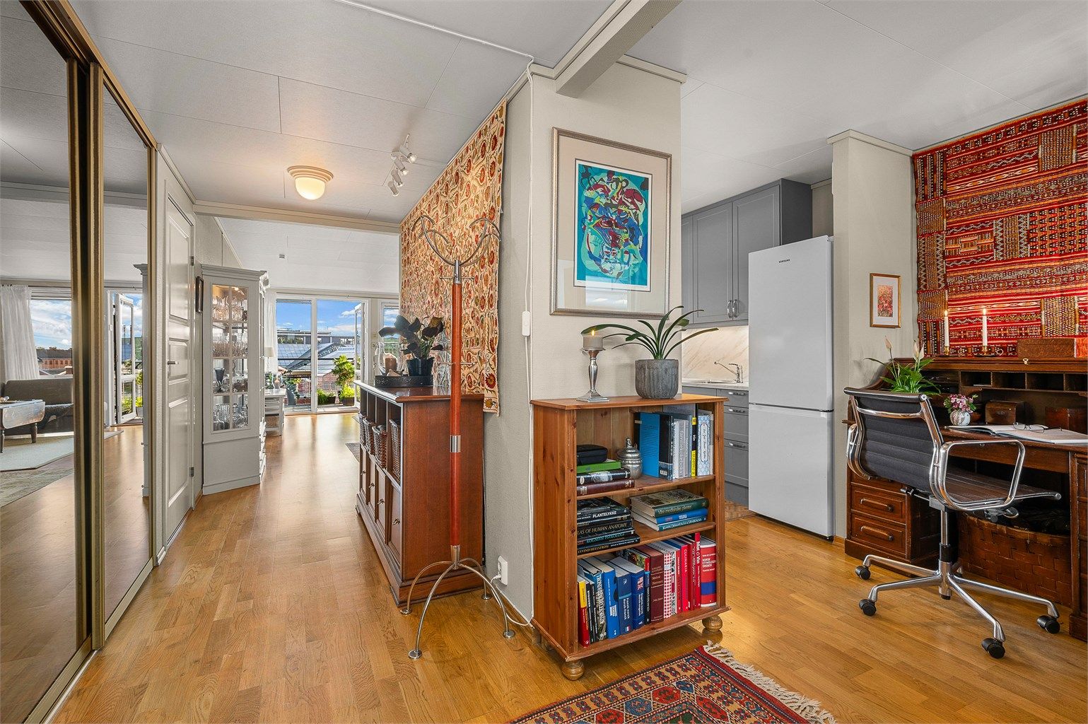 Entré med skyvedørsgarderobe og gjennomgående parkett på gulvet.