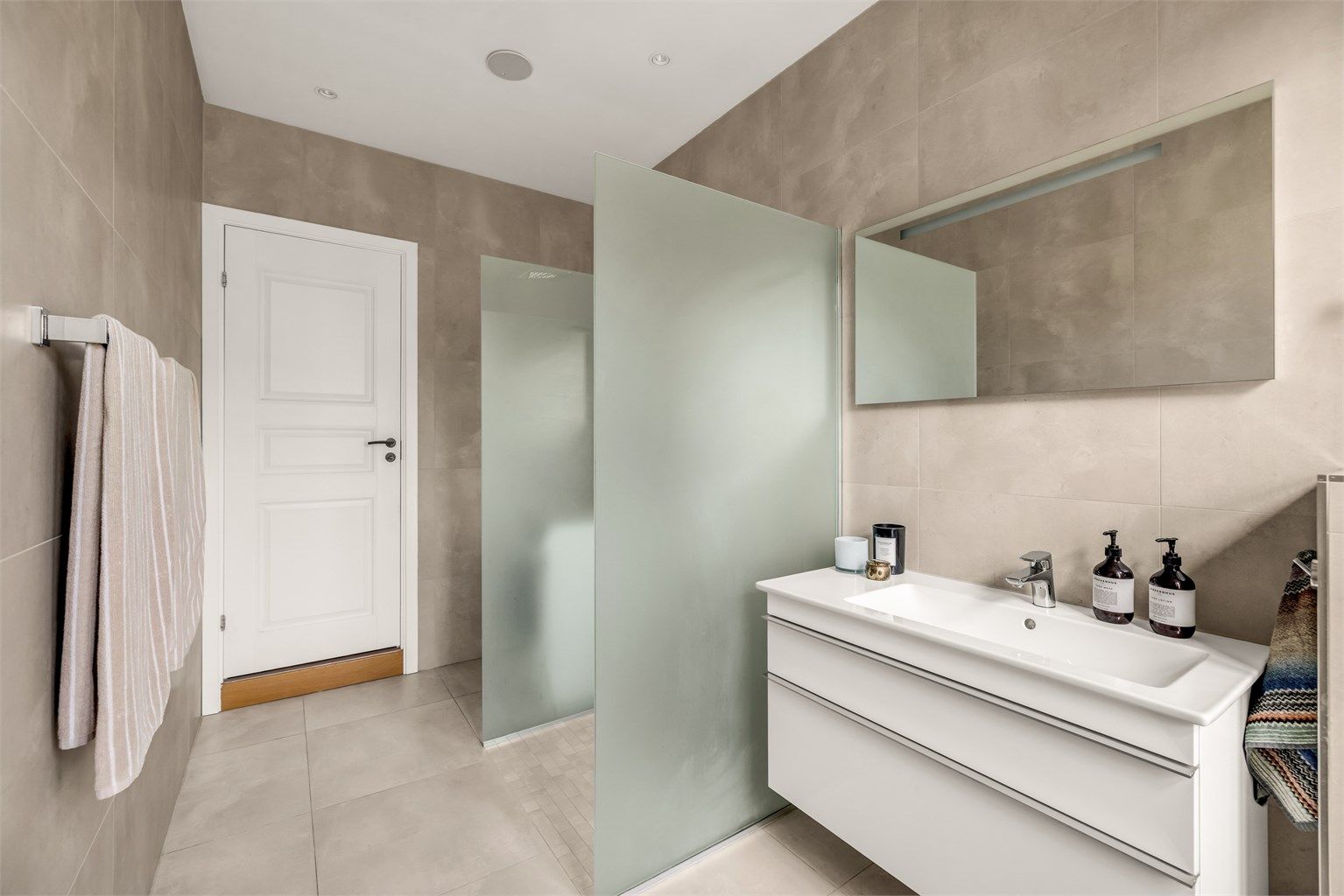 Romslig dusj med dusjvegger i herdet glass. Badet har integrerte høytalere i taket. 