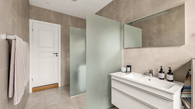 Romslig dusj med dusjvegger i herdet glass. Badet har integrerte høytalere i taket.