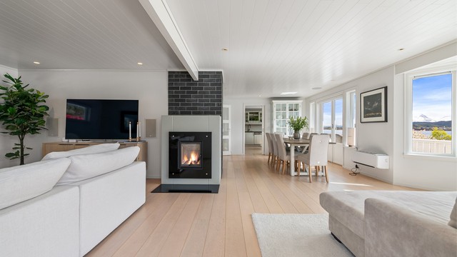 Peis med innsats gir en lun atmosfære. Det er parkett på gulvet og innfelte Sonos-høyttalere i taket
