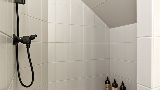 Badet er utstyrt med gulvstående toalett (2025) og dusjnisje med veggmontert dusjarmatur.
