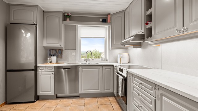 Kjøkken med profilerte fronter, laminert benkeplate fornyet i 2025 og innfelte downlights.