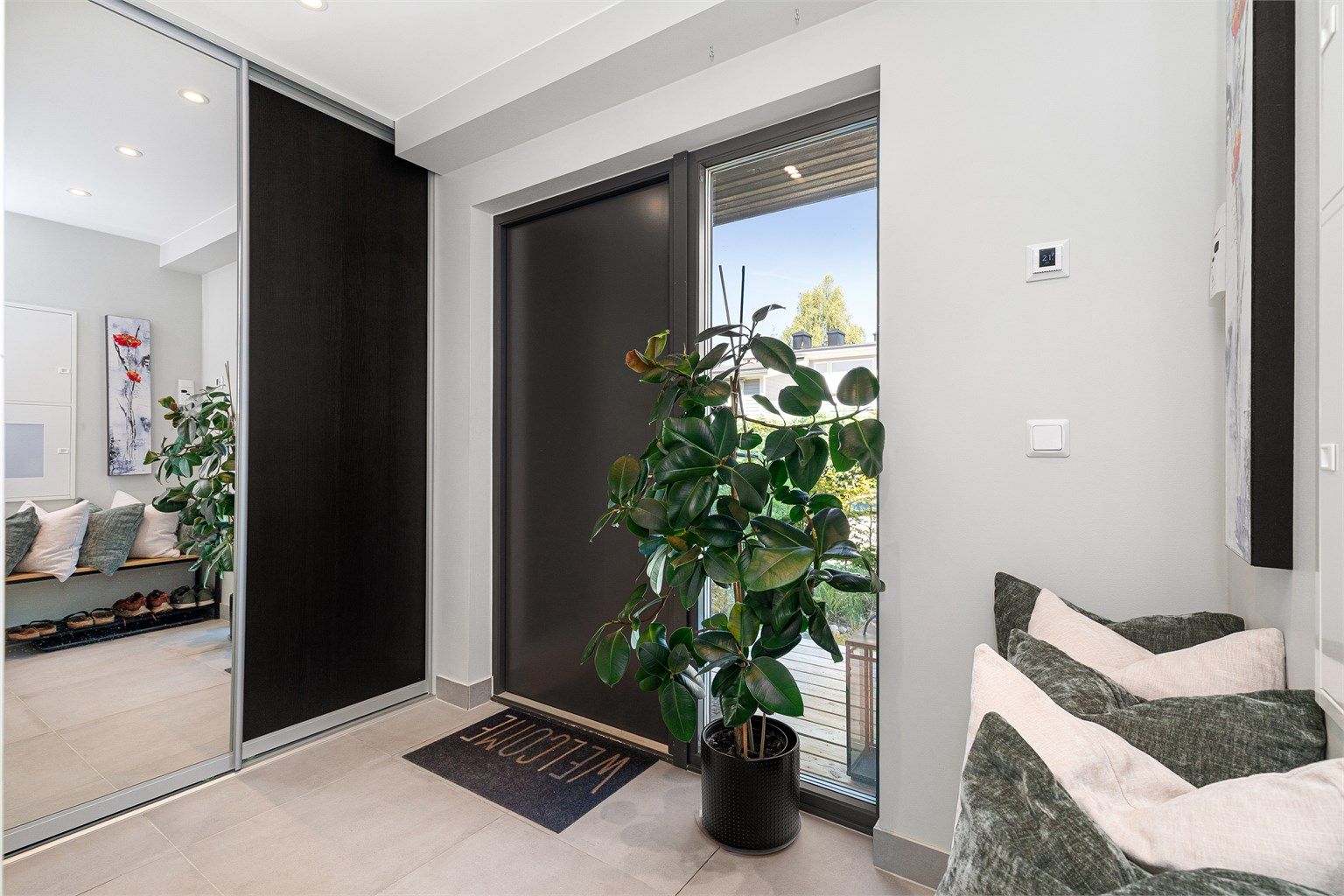 Lys og innbydende entré med flislagt gulv samt romslig skyvedørsgarderobe med plass til yttertøy og sko