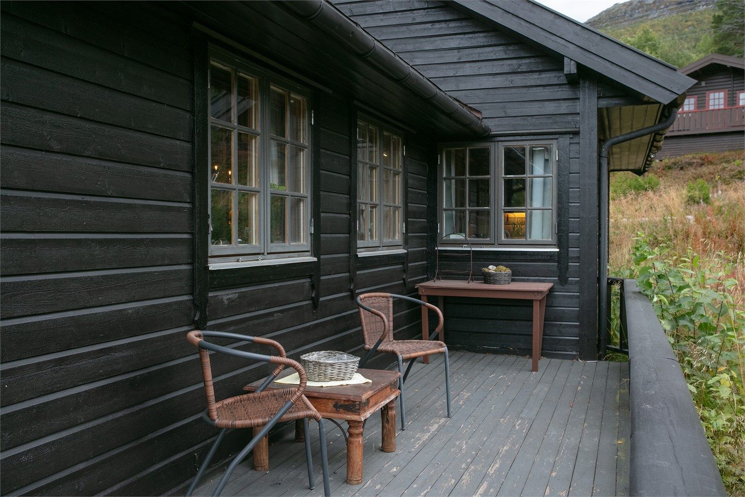 Skjermet sittekrok langs hytteveggen på terrassen.
