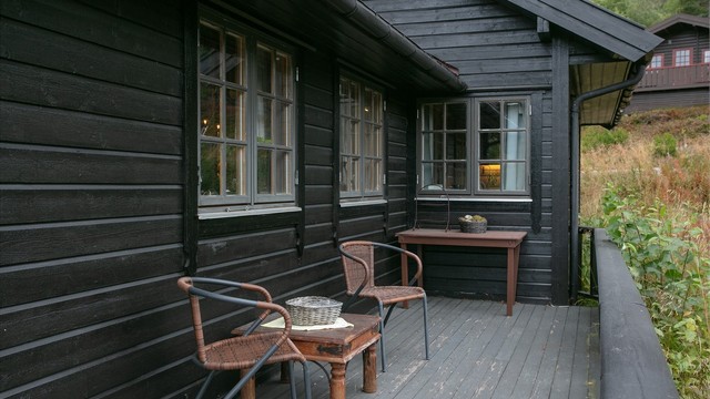 Skjermet sittekrok langs hytteveggen på terrassen.