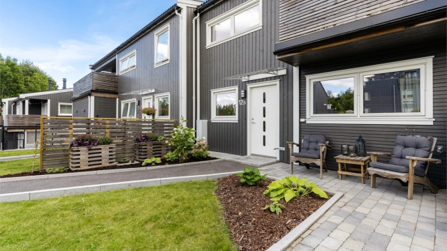 Boligens inngangsparti er pent opparbeidet med plen, belegningsstein og diverse beplantninger. På den sørvestlige siden av bygningen er det en trapp som leder opp til takterrassen.