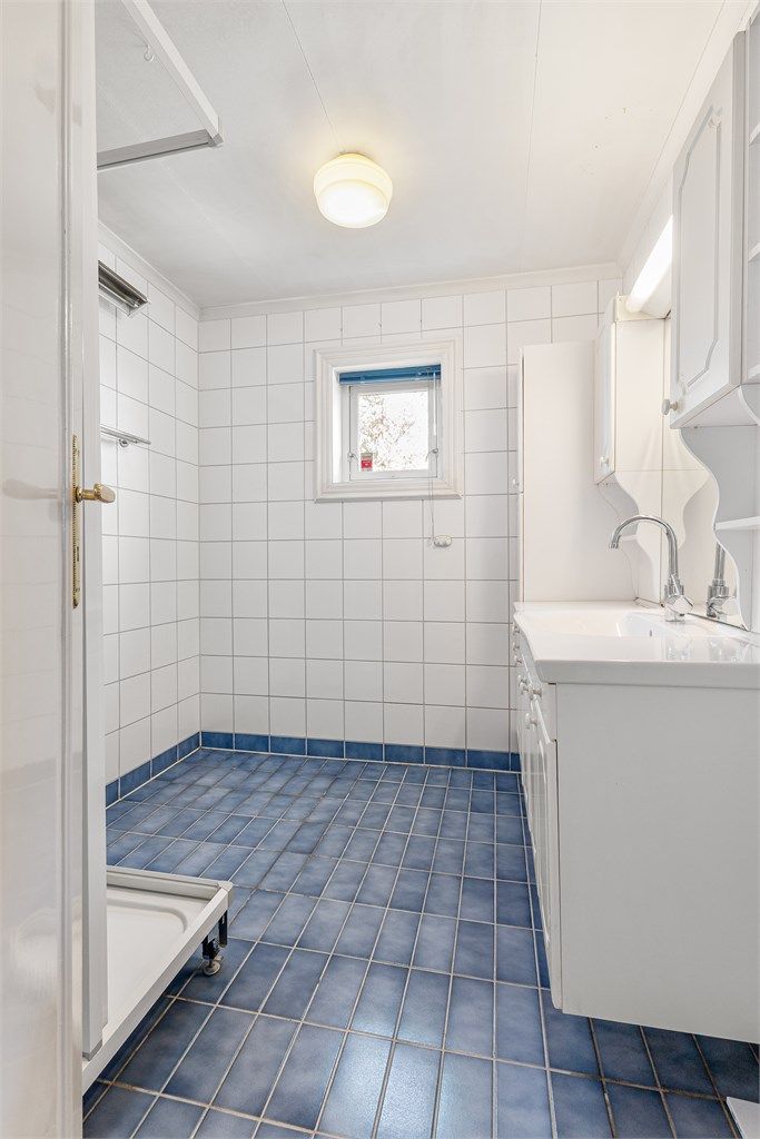 Flislagt bad med vindu som gir naturlig dagslys og mulighet for lufting.