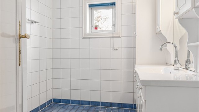 Flislagt bad med vindu som gir naturlig dagslys og mulighet for lufting.