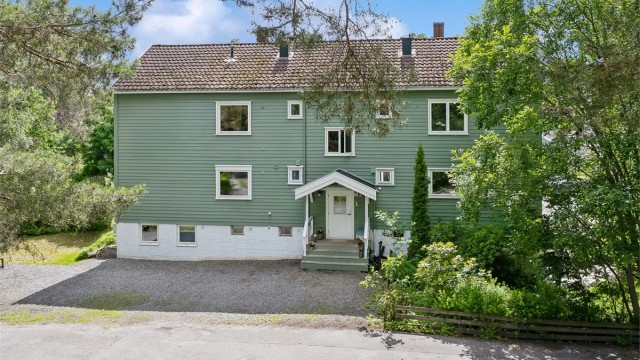 Fasade med inngangsparti og flere biloppstillingsplasser.