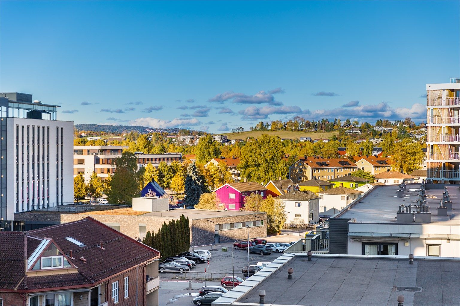 Flott utsyn over fargerik trehusbebyggelse og grønne åsrygger. Foto: Fotograf Digit Media v/Jørgen Sørebø