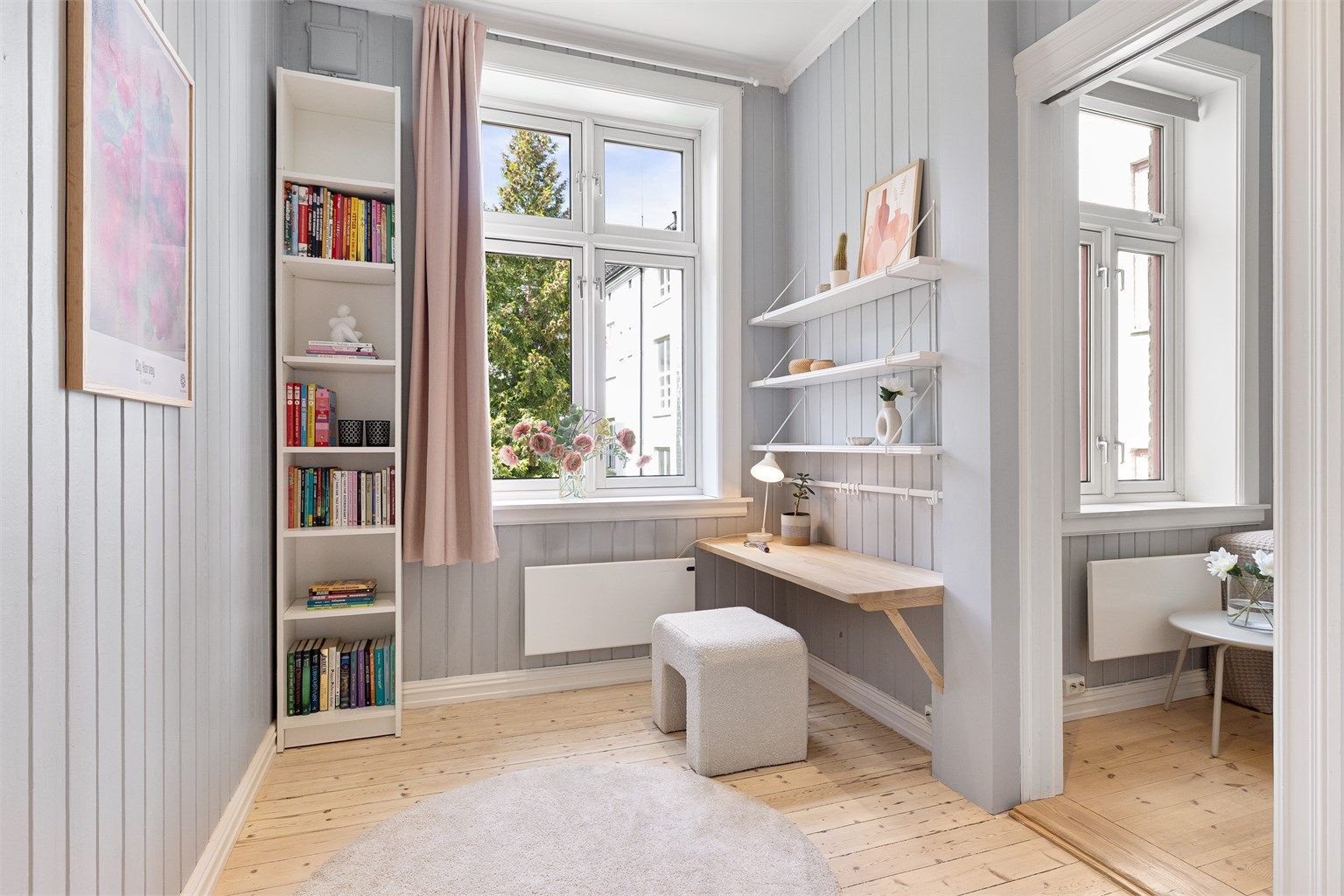 En praktisk arbeidsplass er etablert ved vinduet, med godt dagslys.