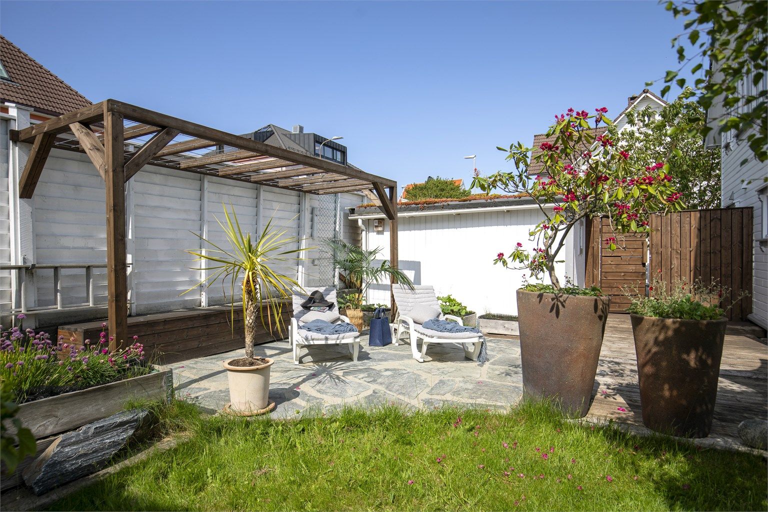 En usjenert del av uteområdet med steinheller og pergola.