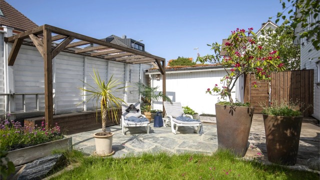 En usjenert del av uteområdet med steinheller og pergola.