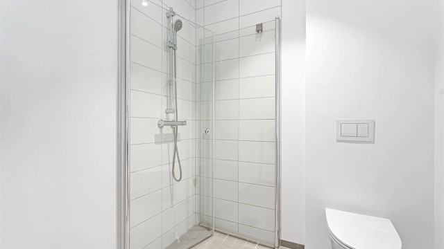 Badet har flislagt gulv og dusjsone