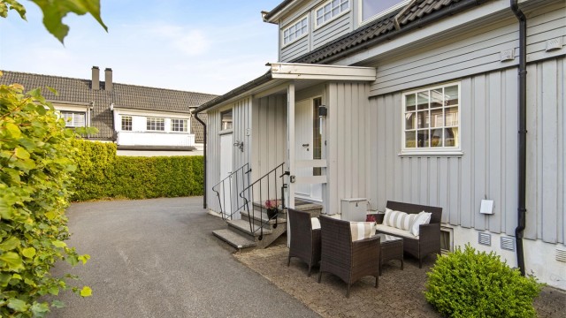 Overbygd inngangsparti, sportsbod og en hyggelig uteplass ved inngangen.