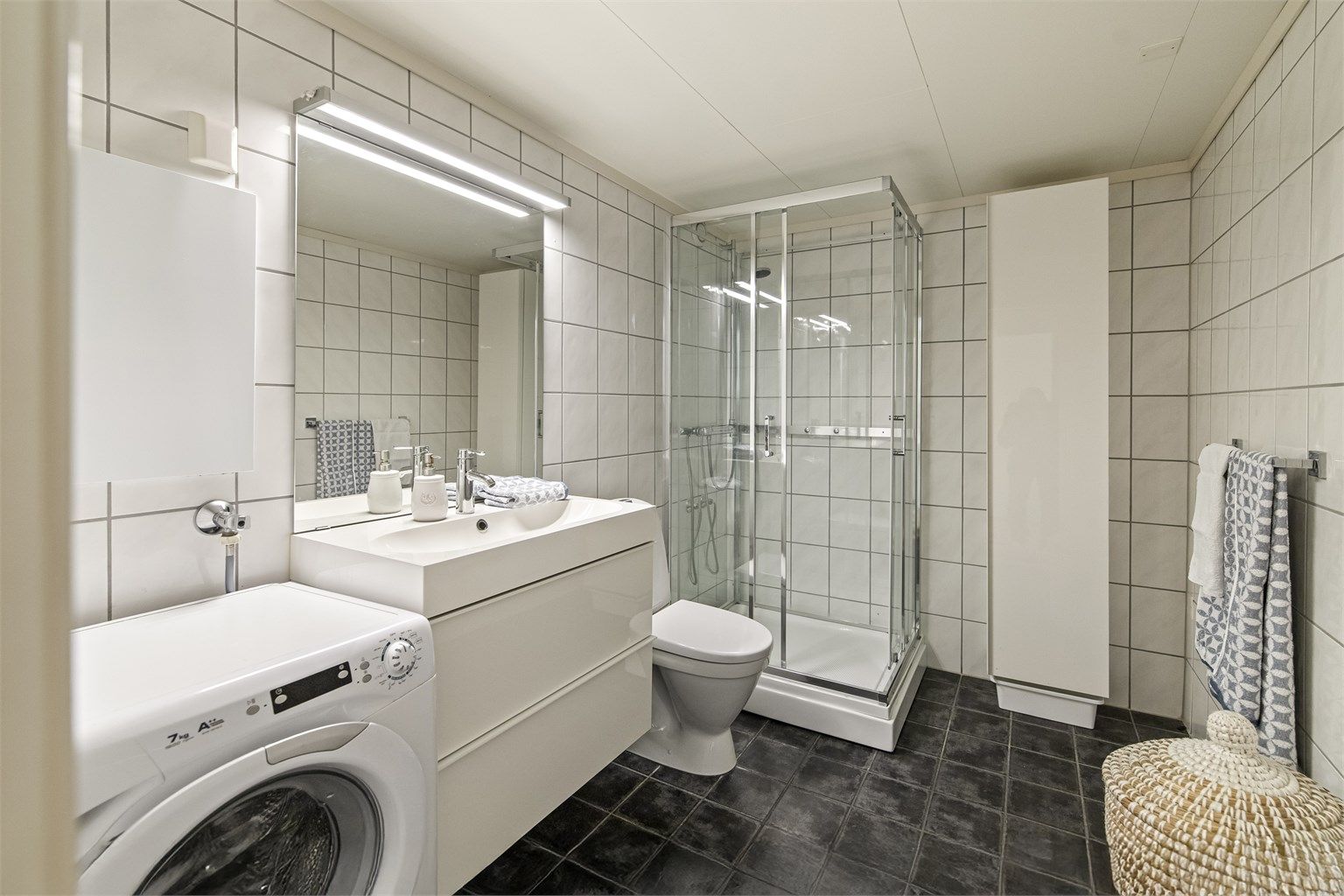 Pent flislagt bad fra ca. 2010 med varmekabler i gulvet. Det er montert innredning med slette fronter, heldekkende servant og ett greps armatur. Speil, overlys og stikkontakt. Dusjkabinett og gulvstående toalett. Badet har også opplegg til vaskemaskin.