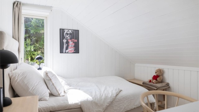 Et av soverommene i andre etasje, med panel på vegger og i skråtak.
