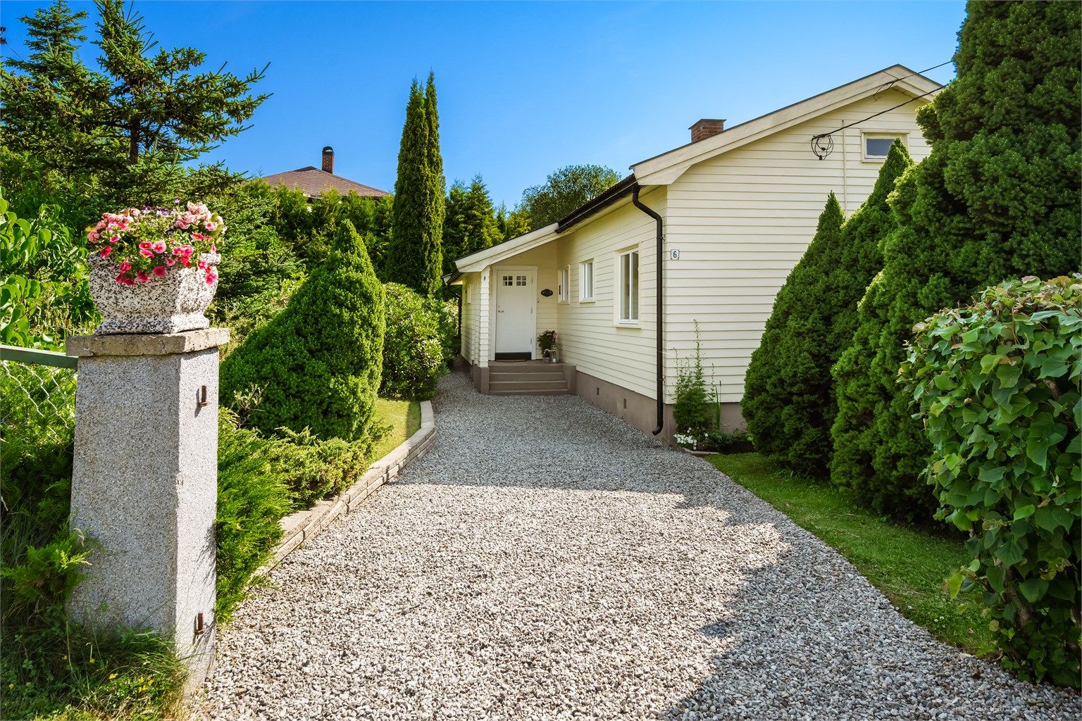 Gruset adkomstvei til boligens overbygde inngangsparti i 1. etasje. 