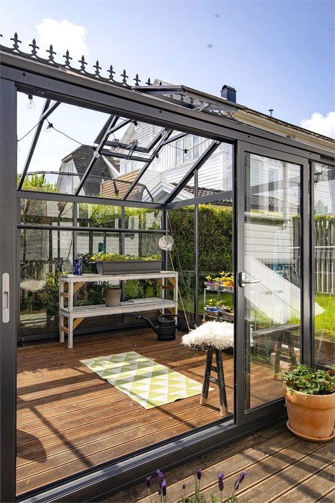 Inne i drivhuset er det god plass til både planter og en liten sittegruppe.