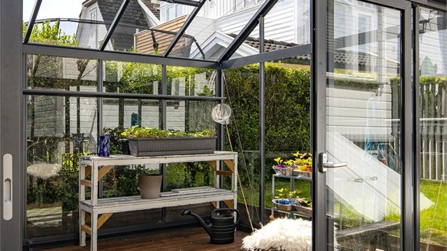 Inne i drivhuset er det god plass til både planter og en liten sittegruppe.