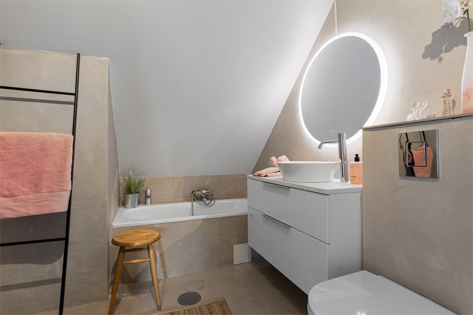 Badet på loftet har overflater i mikrosement, badekar og vegghengt toalett.