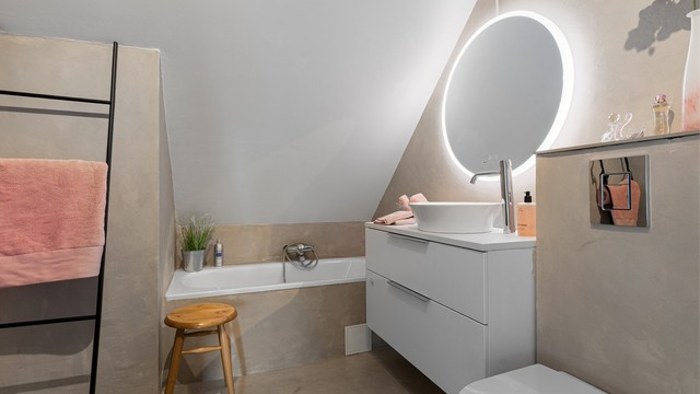 Badet på loftet har overflater i mikrosement, badekar og vegghengt toalett.