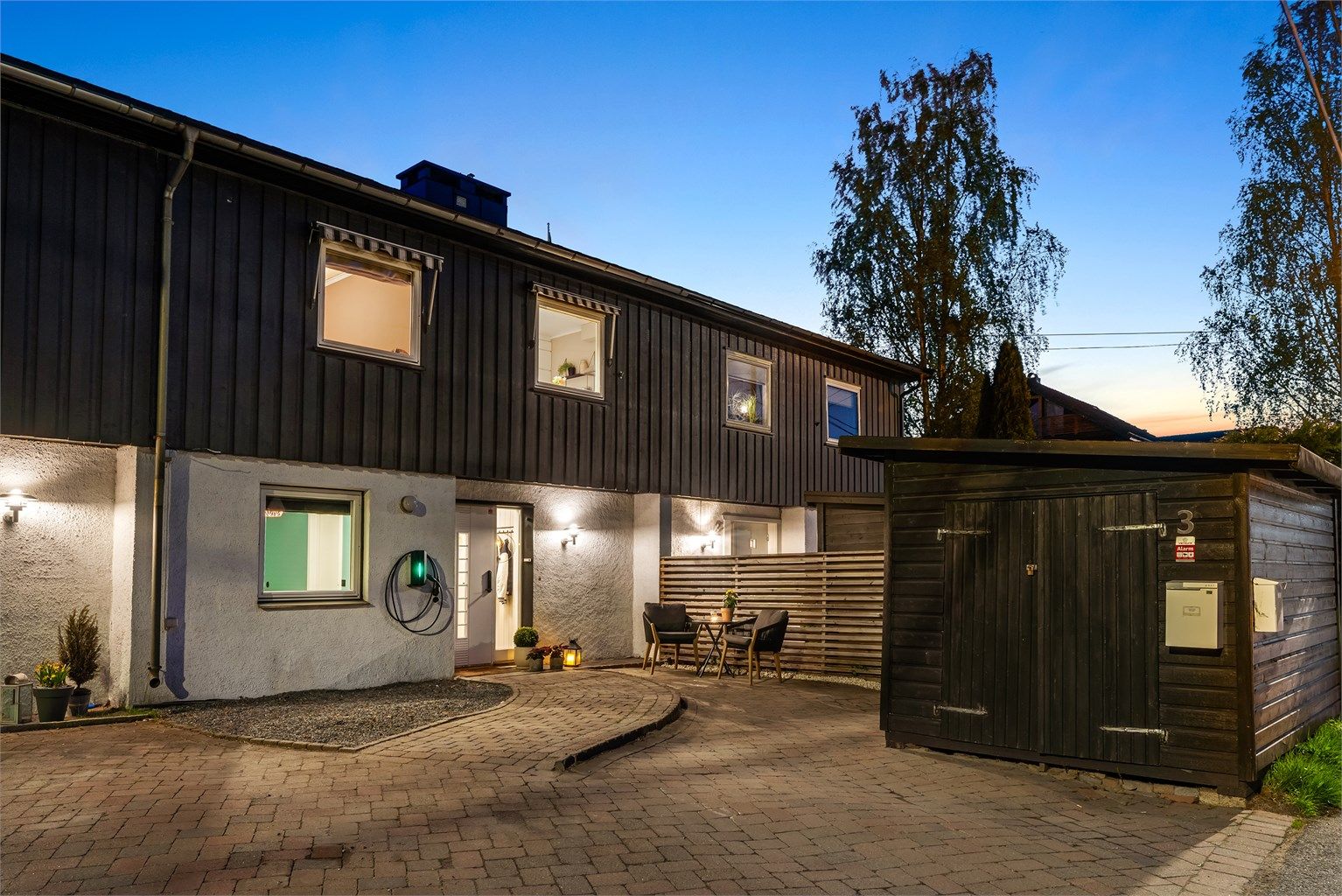 Tomten er pent opparbeidet med belegningsstein, parkeringsplasser med EL-billader, gress og prydbusker, m.m.