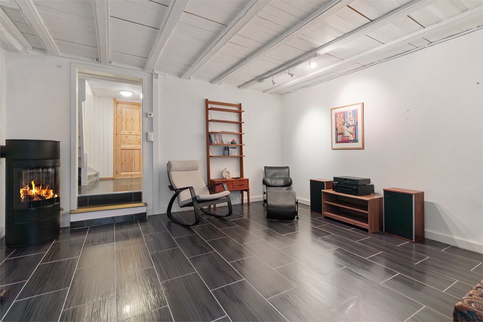 I kjelleren finner du en romslig kjellerstue med egen peisovn og flislagt gulv med gulvvarme.