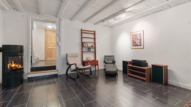 I kjelleren finner du en romslig kjellerstue med egen peisovn og flislagt gulv med gulvvarme.